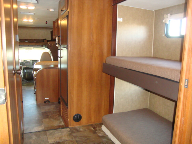The interior of the Coachmen 320BH Class C Bunkhouse features a driver's seat and shelves, providing a functional and organized space for travel essentials
