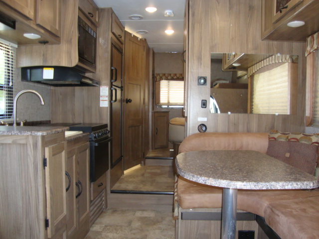 The interior of the Coachmen Freelander 21-RS showcases a beautiful wooden finish throughout, including the kitchen area, bathroom, and all other living spaces, creating a warm and inviting atmosphere