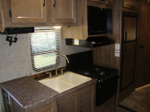 The kitchen area of the Coachmen Freelander 21-RS is fully equipped with all the necessary setups, including a stove, sink, refrigerator, and storage cabinets, providing everything you need for meal preparation on the go